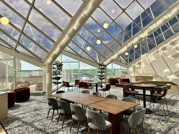 A modern dining room with a glass ceiling and wooden furniture.